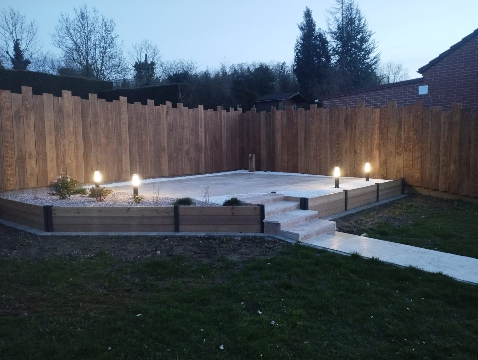 Terrasse bois avec bornes d'éclairage extérieur au crépuscule — JS Aménagement